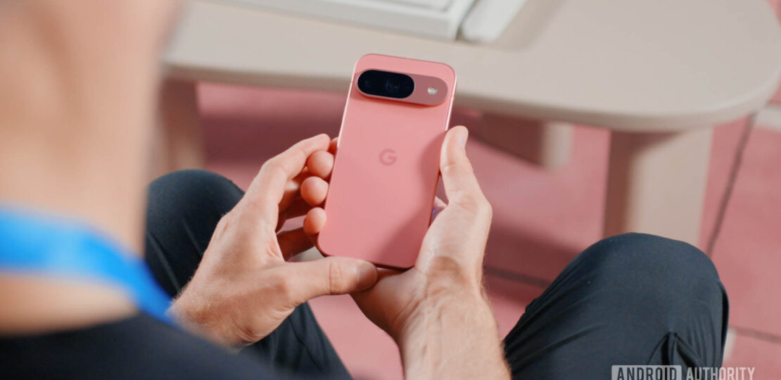 Google-Pixel-9-in-Peony-in-a-mans-hands-as-he-examines-the-back-of-the-device.jpg